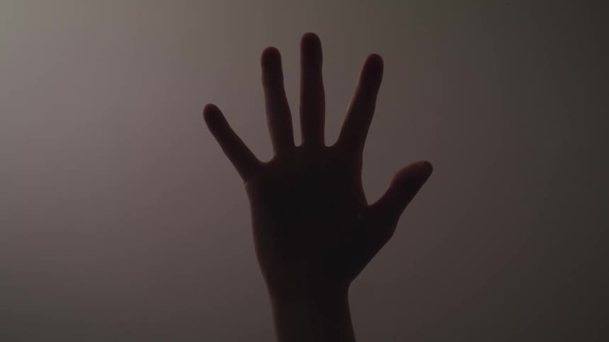 Hand reaches up to press palm side down against glass