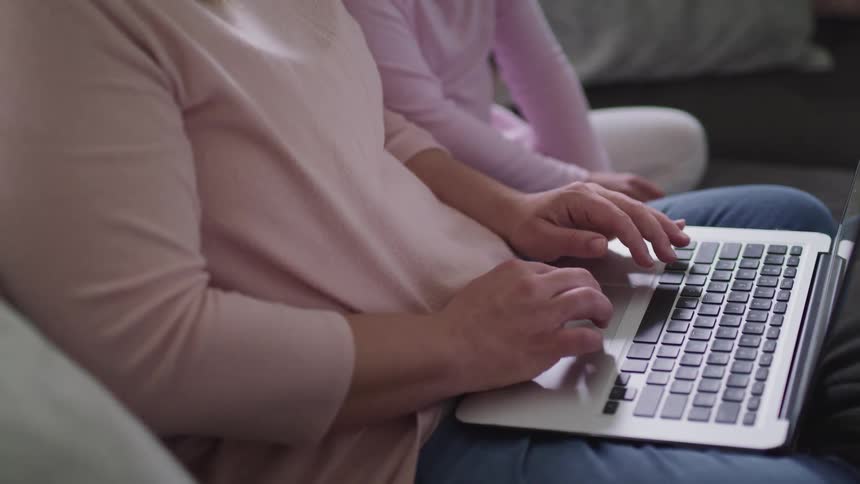 A man and his daughter use a laptop together on the couch