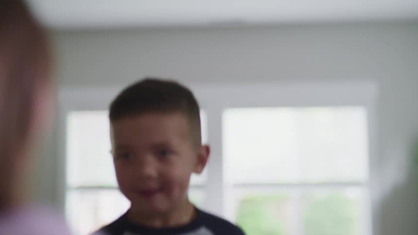 Children with grey and pink long sleeve t shirt jump on a sofa in the living room