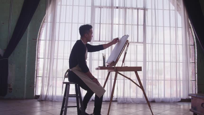 A man is sitting and painting