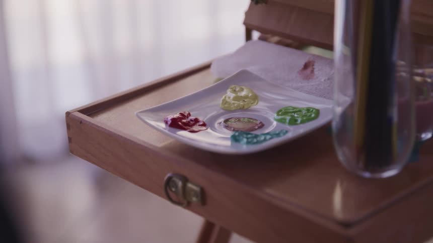 A paint dish resting on the tray of a painting easel