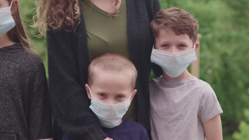 A mother and her children pose for a photograph while wearing face masks