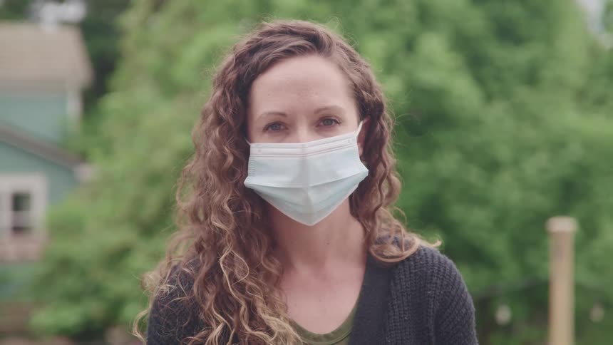 A woman is outdoors while wearing a face mask