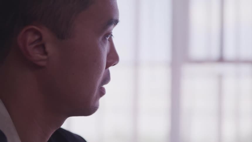 Close up of a mans face while he paints on canvas at home