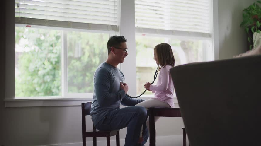 Man teaches a little girl how to use a stethoscope at home