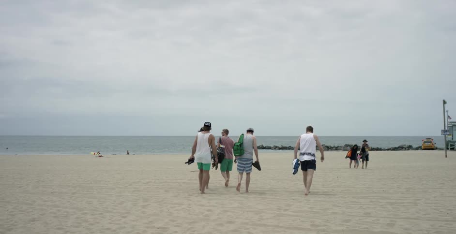A group of men walking across the sand at a beach