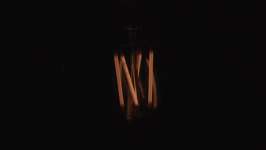 Filament brightens and darkens as light bulb turns on and off in darkness