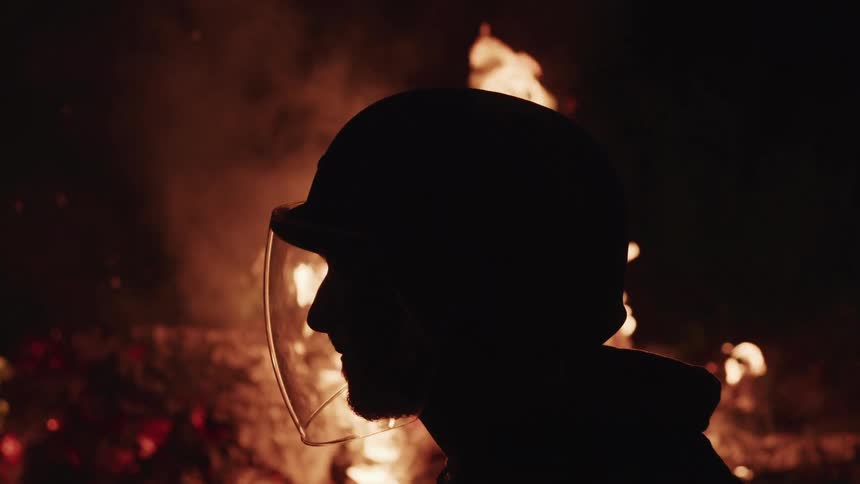 A firefighter standing in front of a large fire