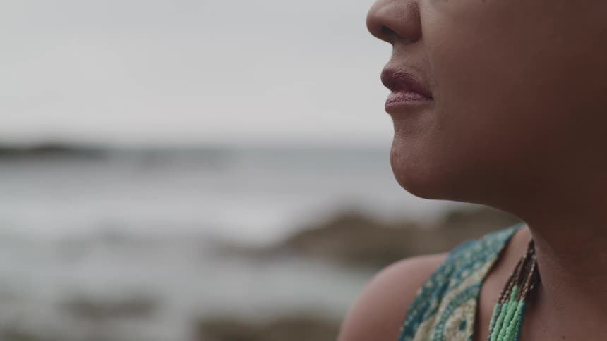 A woman watches the ocean on a cloudy day
