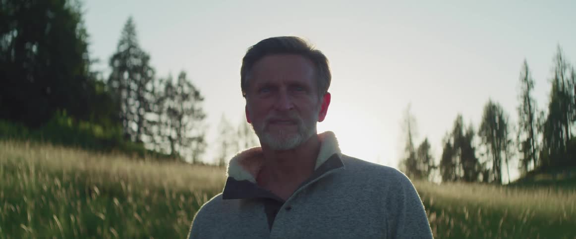 A man is standing outdoors in a wooded area