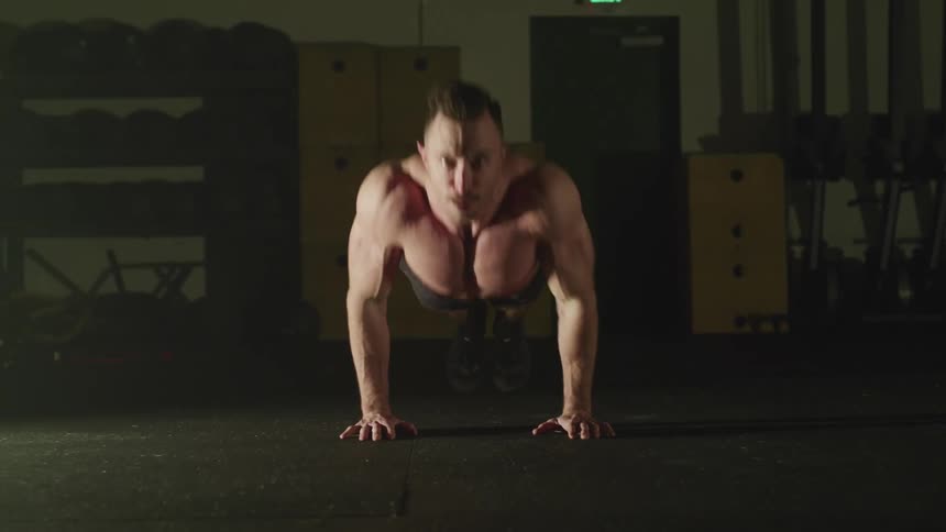 Muscular strong man does push ups in a gym