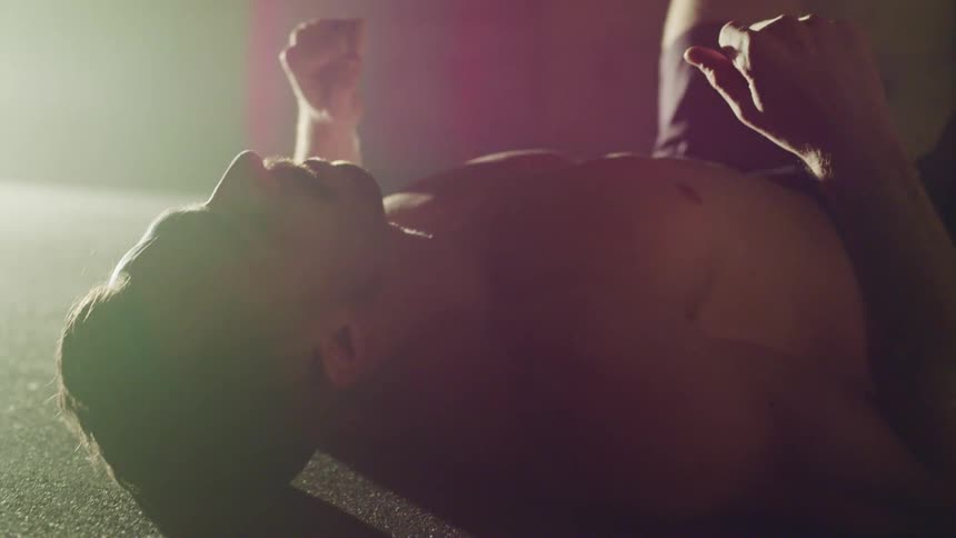 A shirtless man catches his breath while lying on his back