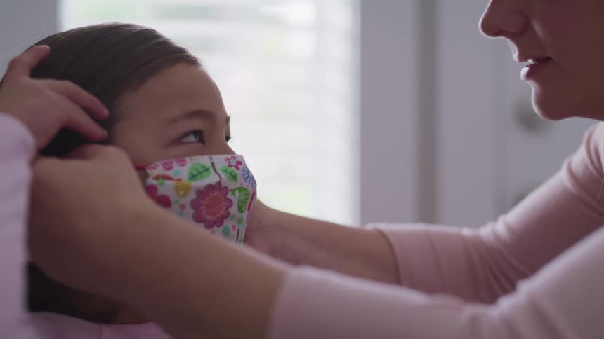 A mother puts a mask on her daughter