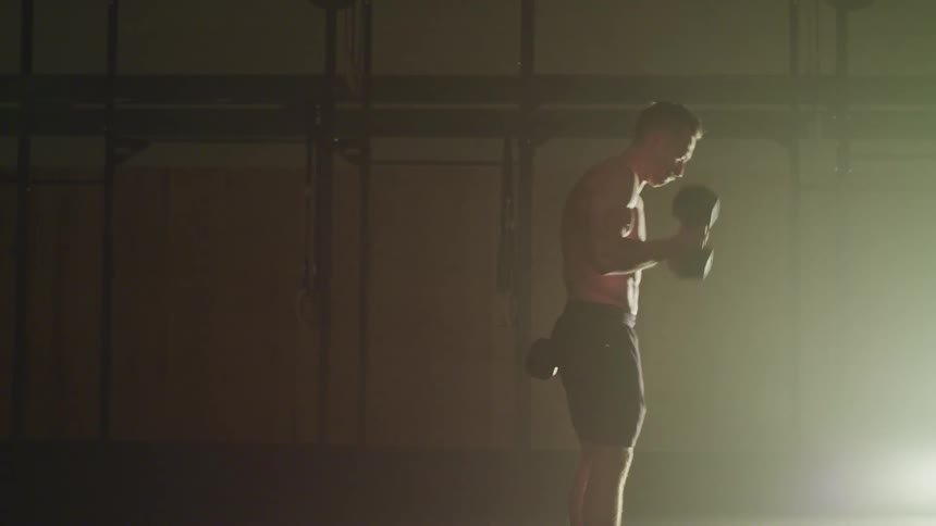 A man is working out in a gym while lifting weights