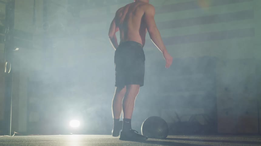 A man exercises by throwing a medicine ball around