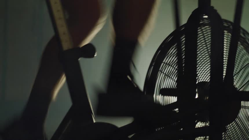 A man begins pedaling very quickly while atop a stationary exercise bicycle