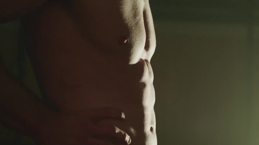 Shirtless man clenches his abdomen muscles