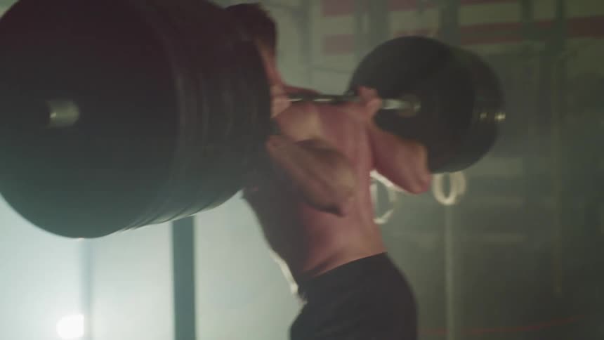 A man in a gym picking up weights and doing squats
