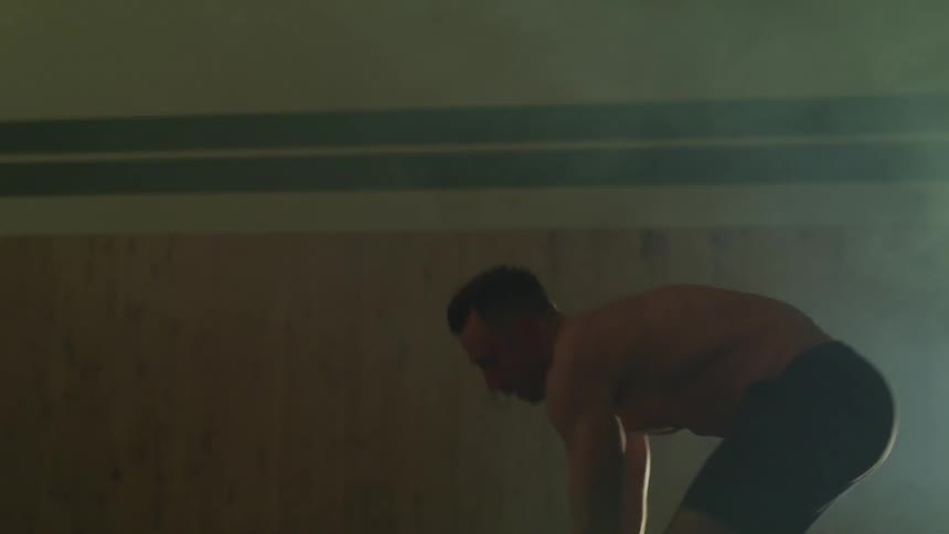A man is working out indoors while using equipment