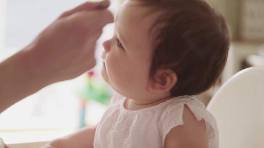 A baby is being fed at home