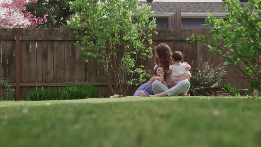 A mother is playing with her children in the backyard