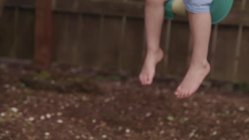 A persons feet are seen swinging in the yard