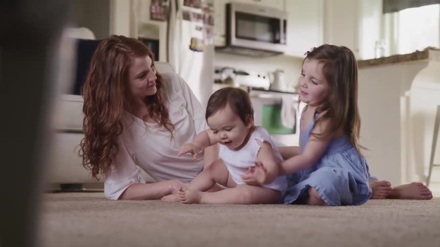 Mother daughter and baby play and hug on floor