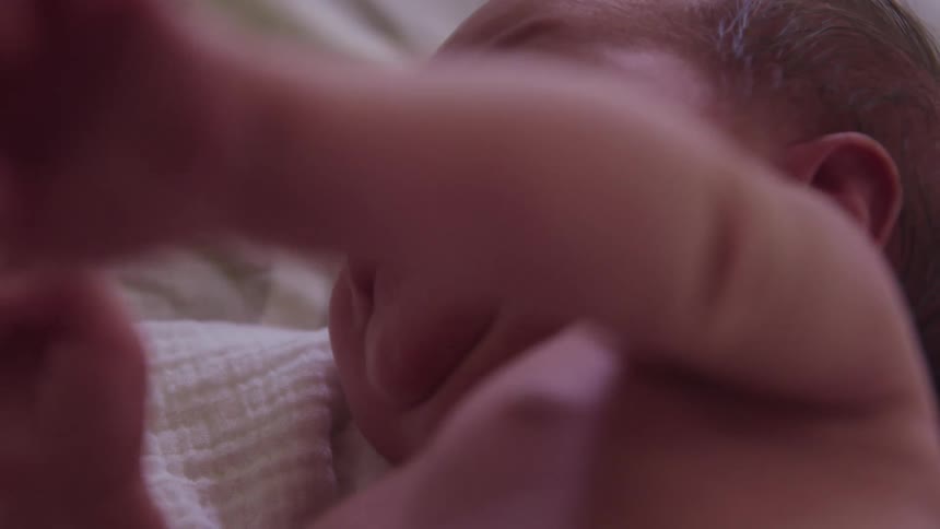 A baby laying on a bed with a blanket and pillow