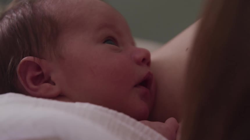 Close up of the face of a newborn baby in his mothers arms