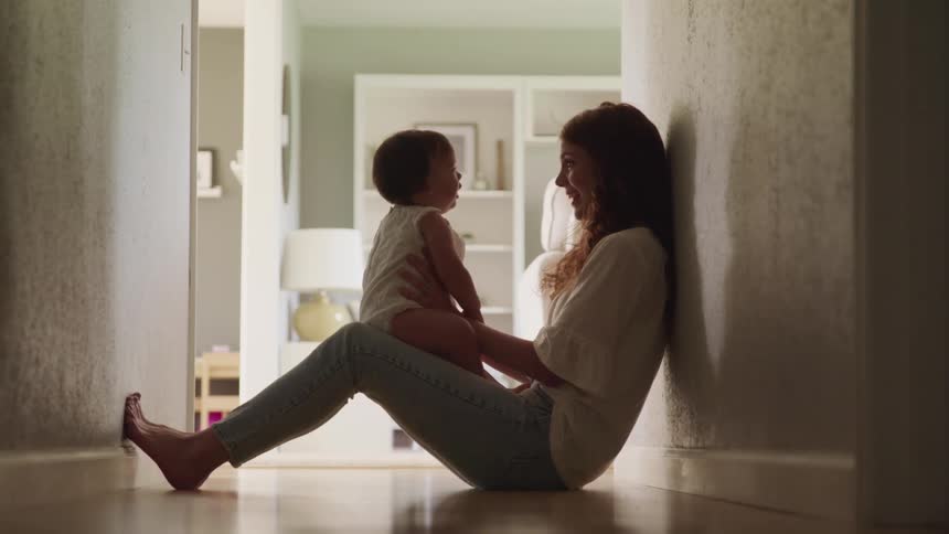 A mother holds her baby sitting in the hallway