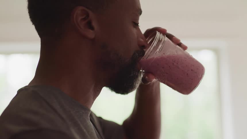A man drinks a smoothie at home