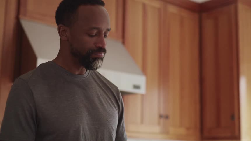 A man is drinking juice in his kitchen