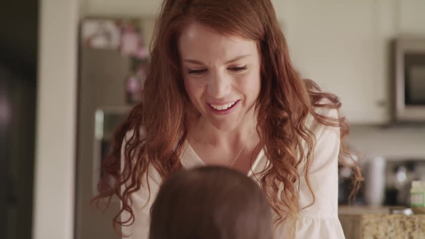 A woman plays with a baby in a kitchen