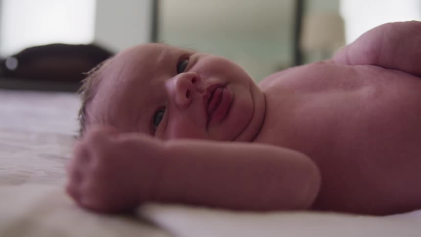 New born baby laying on a bed in the bedroom at home