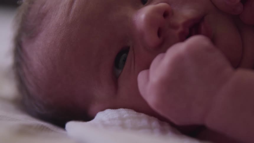 A baby laying on a bed with a blanket