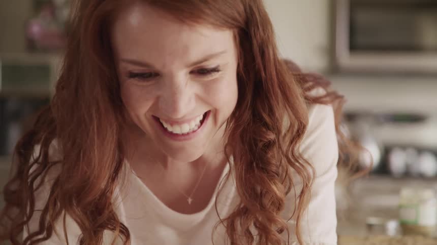 Close up of a ginger woman face happily smiling at someone at home