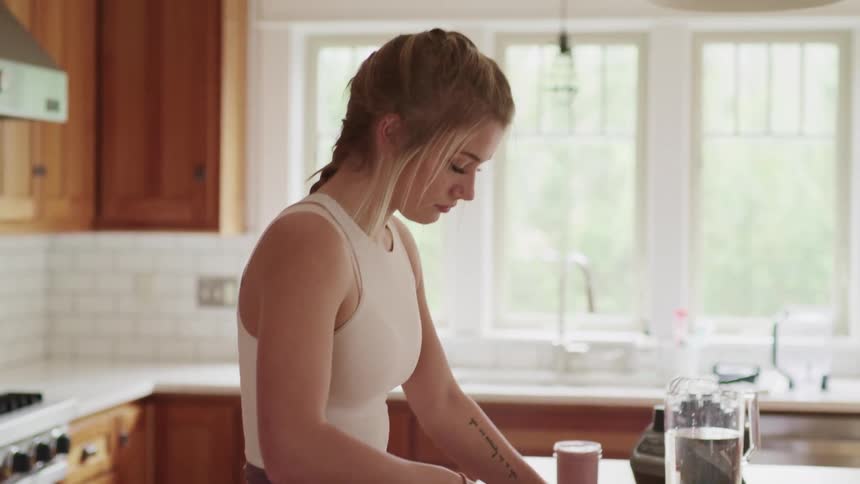 A young women chops vegetables on a cutting board in the kitchen