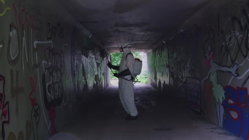 Person spraying down a wall covered in graffiti