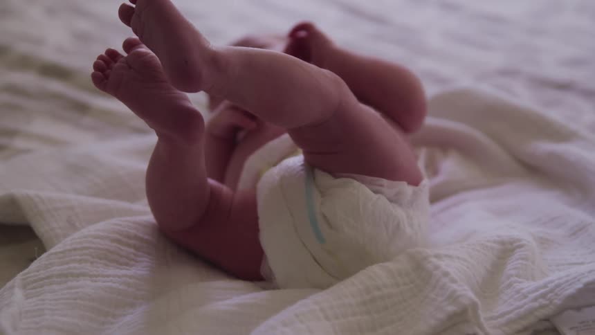 A baby lies on a blanket on top of a bed