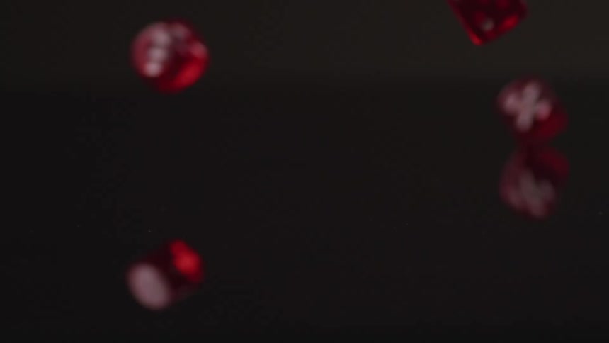 Red dice with white dots scatter as they are dropped onto a black surface