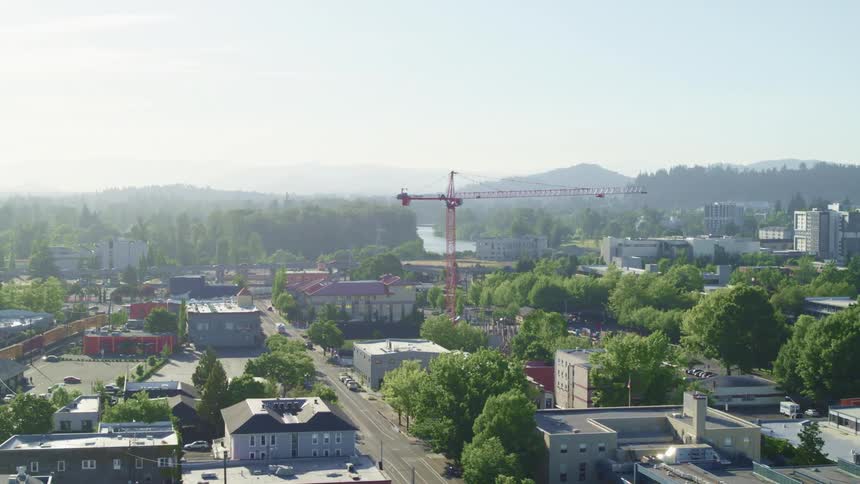 Construction crane in the middle of a small city near the mountains