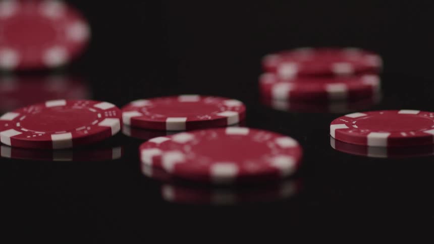 Red and white poker chips fall onto reflective grey surface