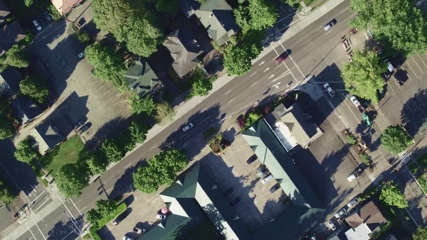 Vehicles travel down a neighborhood road in a city