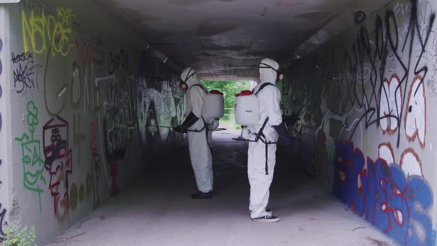 Two people are cleaning graffiti in the tunnel
