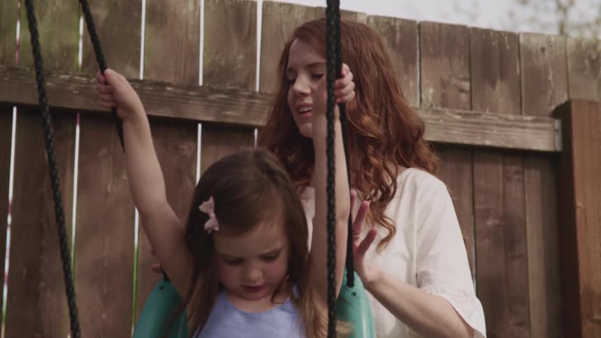 A mother pushing her child on a swing