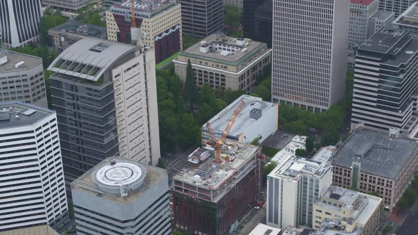 An aerial view of a construction crane on top of a building in a downtown area