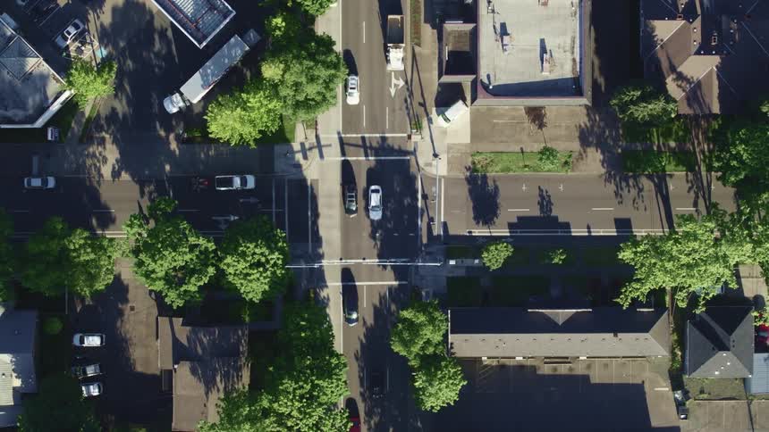 Aerial view of an intersection and vehicles driving down in the city