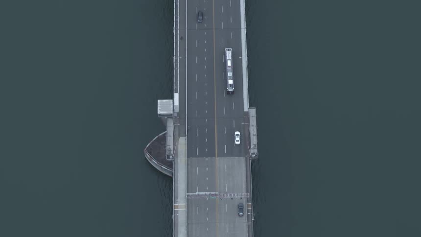 Several vehicles travel along a lengthy bridge over a large body of water