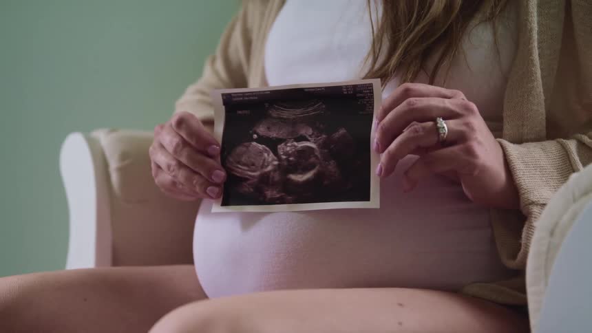 A pregnant woman is displaying her sonogram picture