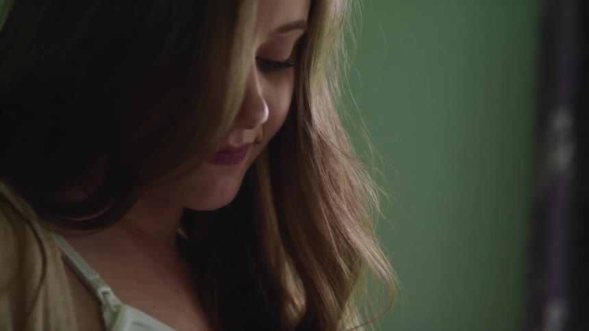 Pregnant woman with brown hair looks down